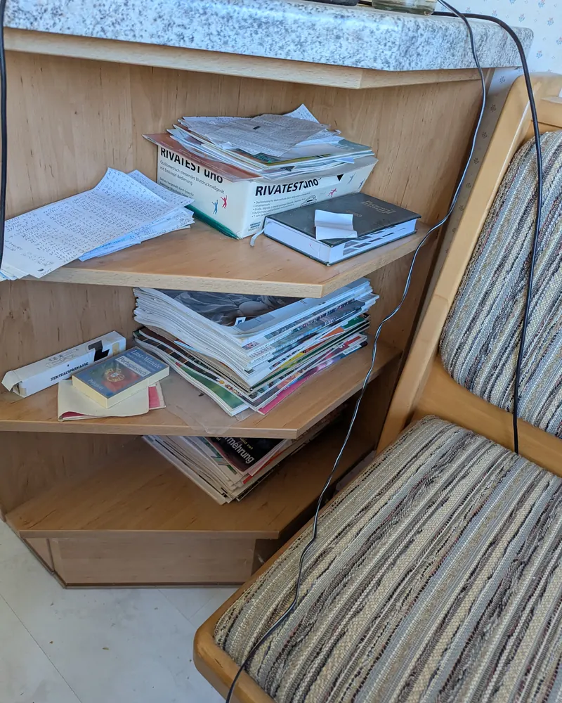 Eckregal vorher: Zeitschriften und Prospekte in unordentlichen Stapeln, ein Kabel quer darüber.